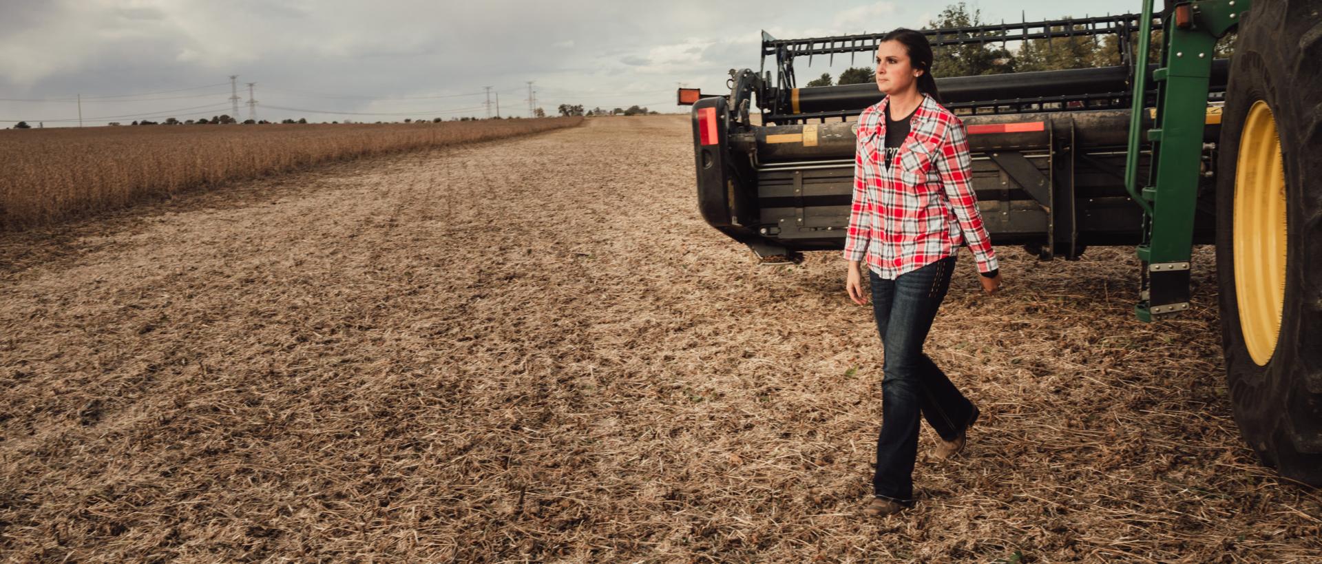 Woman walking out of combine in harvested field.